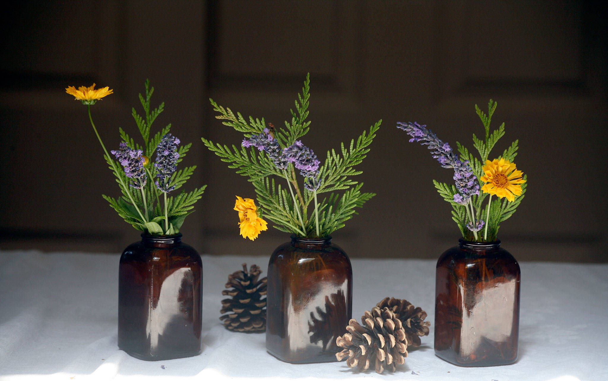 Adding single stems of coreopsis and lavender to each jar adds a little pop of color. When the flowers fade, take them out and the cedar will still last for days. (Vanessa McVay / The Herald)