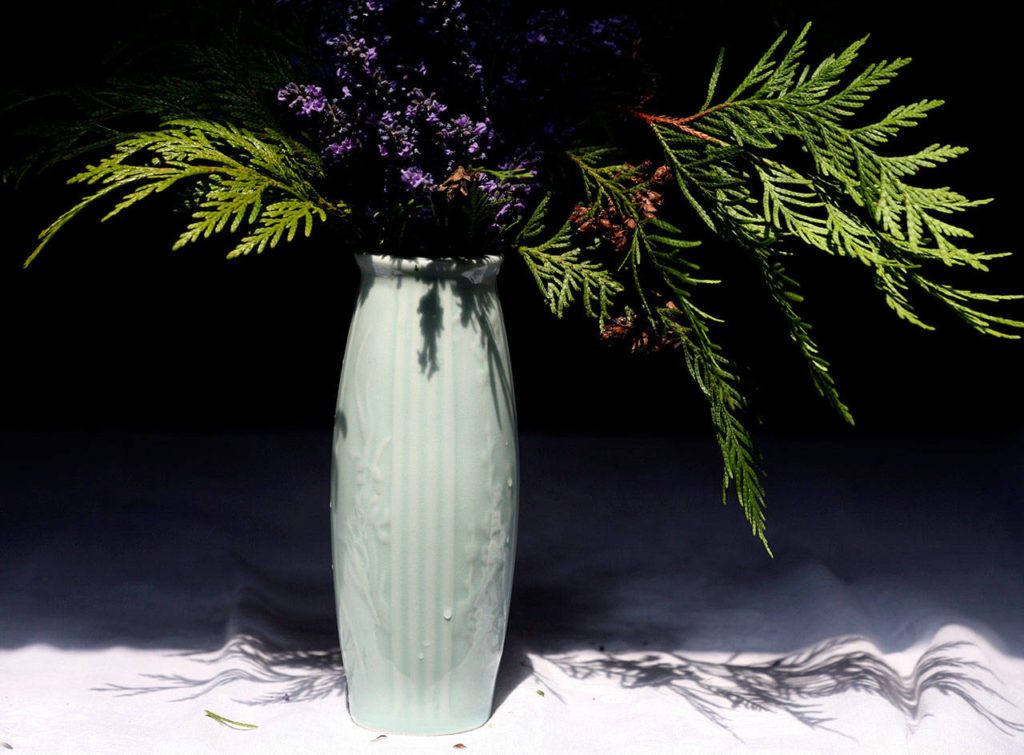 The pastel shade and simple, vertical form of this ceramic vase puts the visual emphasis on graceful, complex cedar branches. The addition of English lavender creates a fragrant and exceptionally long-lived arrangement, as long as the stems get retrimmed and the water changed every few days. (Vanessa McVay / The Herald)
