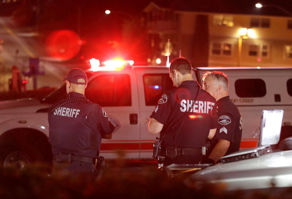 Law enforcement officials stand at a staging area late Friday at the ferry terminal in Steilacoom, near where the Coast Guard was responding to the apparent crash of a stolen Horizon Air plane. (AP Photo/Ted S. Warren) 
