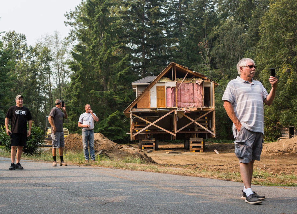 Local residents watch as a house is moved Wednesday down Bellflower Road in Bothell. (Olivia Vanni / The Herald)
