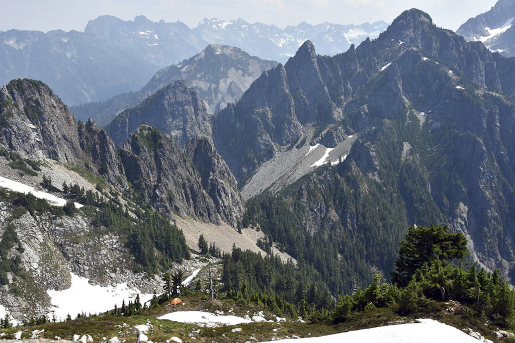 The view of east from Vesper Peak shows a climber’s camp and Headlee Pass, at center, as well as the rugged terrain of the Glacier Peak Wilderness. (Caleb Hutton / The Herald)
