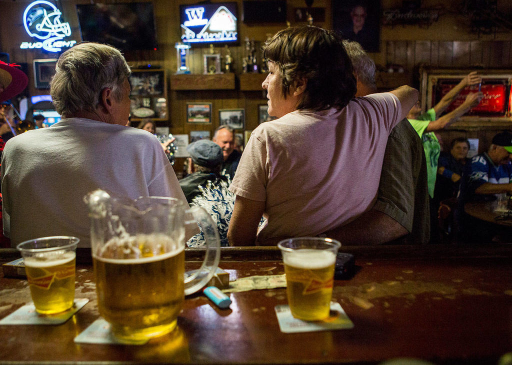 Erin Wilson (left) and Howard Southern (right) embrace while they enjoy their beer during the Kuhnle’s Tavern centennial celebration Saturday in Marysville. (Olivia Vanni / The Herald)
