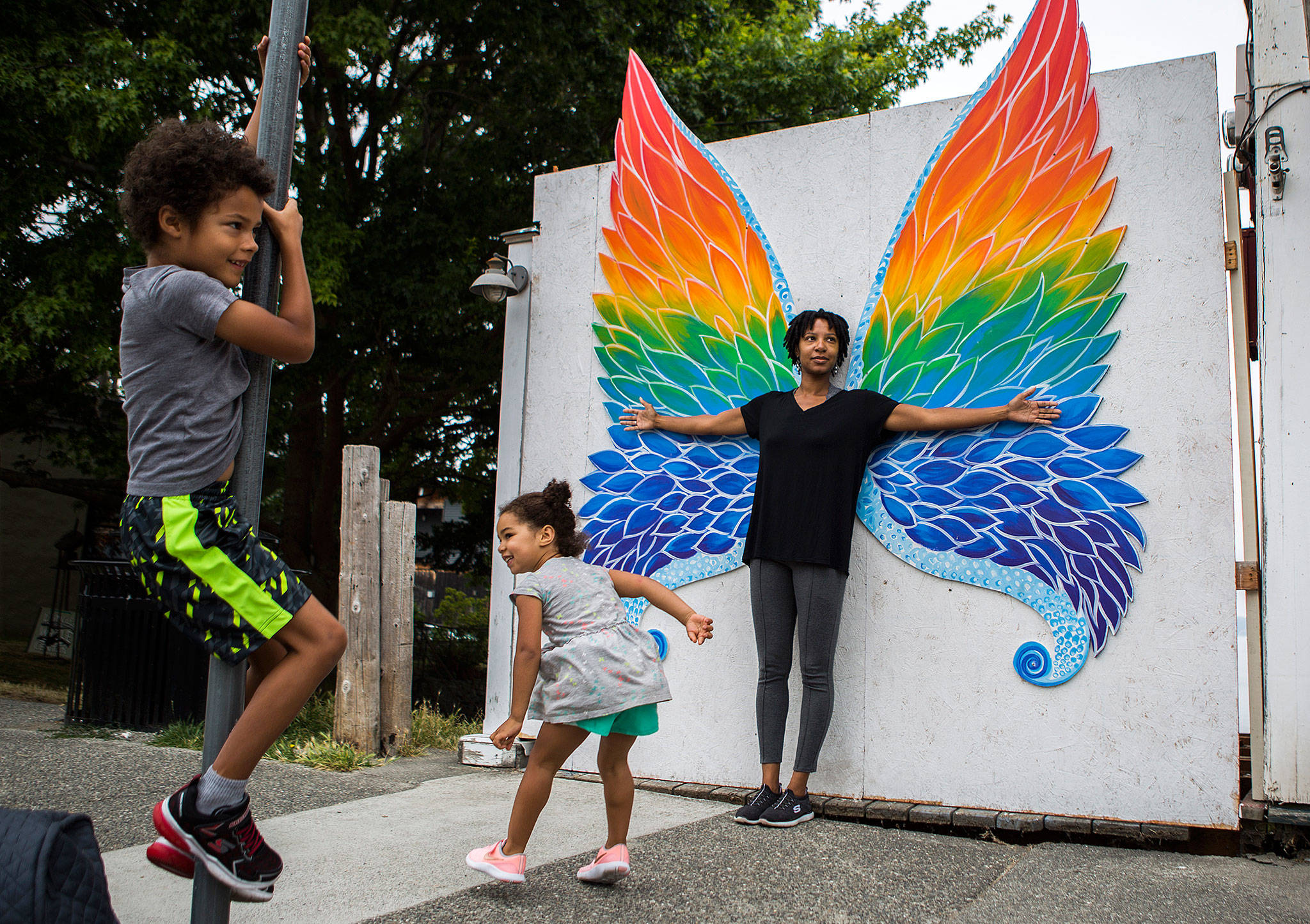 Lindsey T.H. Jackson, right, and her children, Cohen, 6, left, and Taylor, 4, center, pose for pictures in front of the butterfly wing art installation. (Olivia Vanni / The Herald)