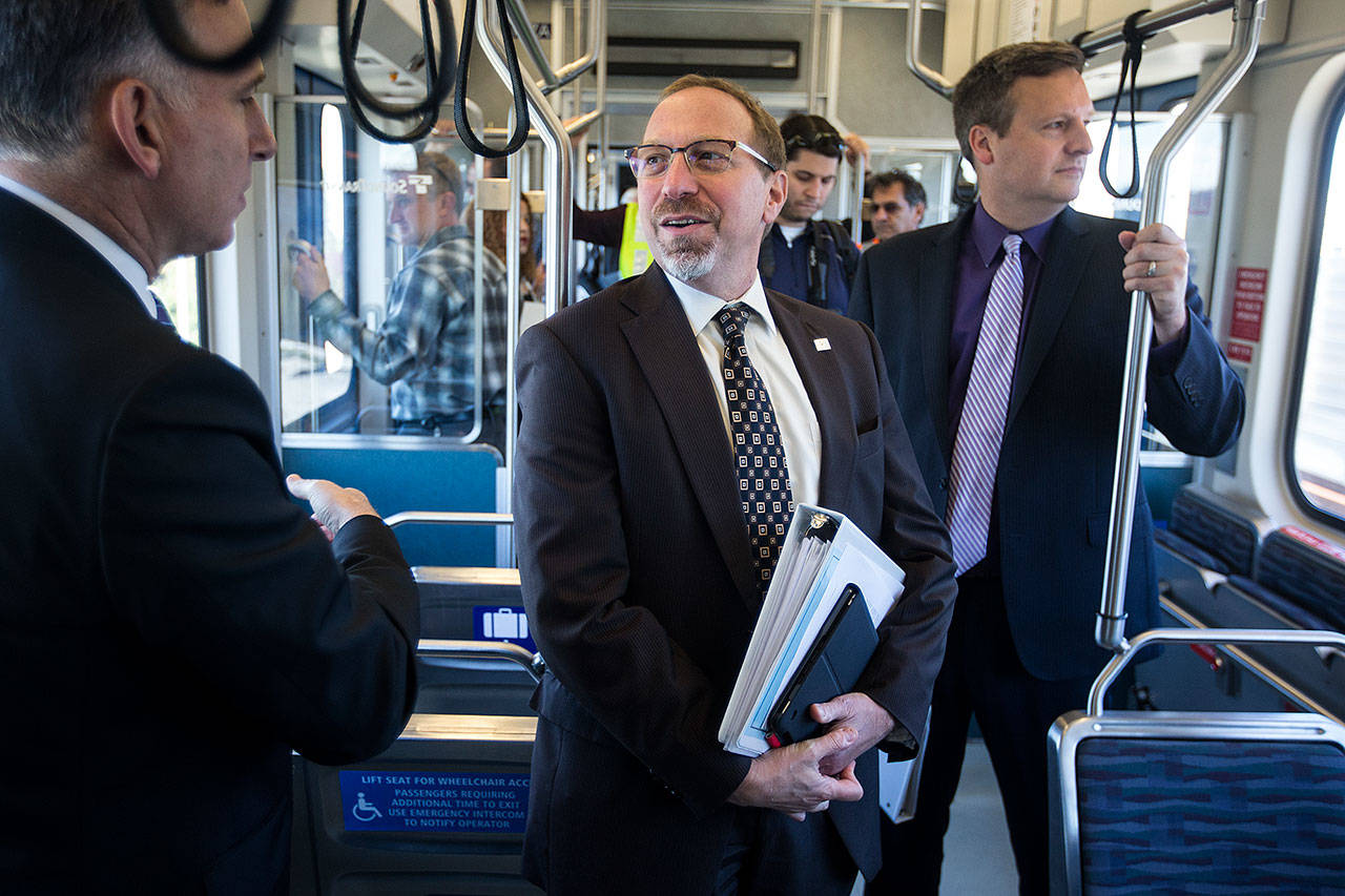Sound Transit CEO Peter Rogoff (center) talks with King County Executive Dow Constantine while riding the light rail from Angle Lake station in September 2016. (Ian Terry / Herald file)