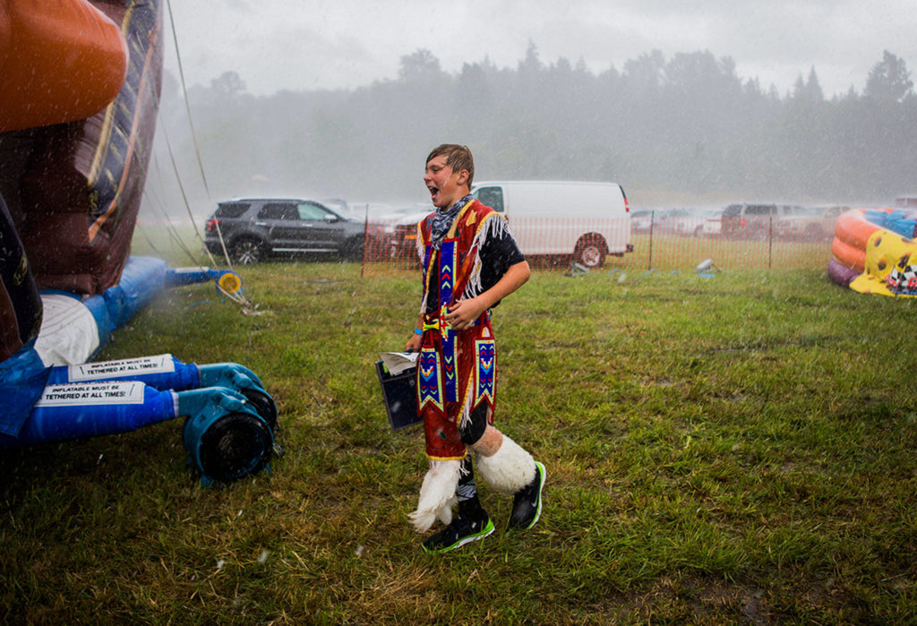 Gage Boser laughs as he gets stuck in a rainstorm at the Festival of the River Pow Wow on Aug. 11, 2018 in Arlington, Wa. (Olivia Vanni / The Herald)
