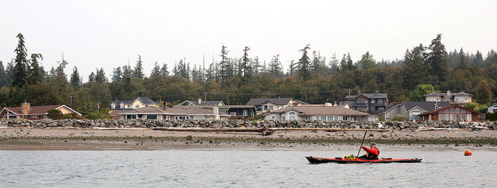 Don Crook, vice-president of the Washington Water Trails Association, rows pass a private beach on a trek to Hope Island located off the coast of La Conner. (Lizz Giordano / The Herald)
