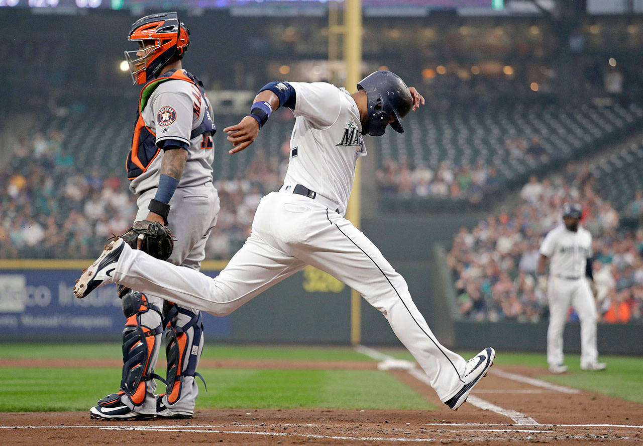 Seattle’s Robinson Cano crosses home plate as Houston’s Martin Maldonado looks on during the first inning of the Astros’ x-x win over the Mariners on a hazy Monday night in Seattle. (AP Photo/Elaine Thompson)