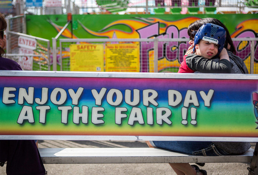 Gregory Lentz, 9, holds onto his mother, Lisa Lentz, as they sit in a quiet area of the fairgrounds during the Morning of Dreams at the Evergreen State Fair on Wednesday in Monroe. (Olivia Vanni / The Herald)
