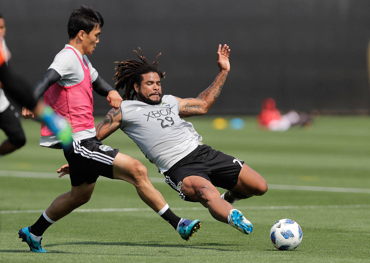 Sounders defender Roman Torres (right) slides on for the ball in front of defender Kim Kee-hee during pracitce on Aug. 8, 2018, in Tukwila. (AP Photo/Ted S. Warren)