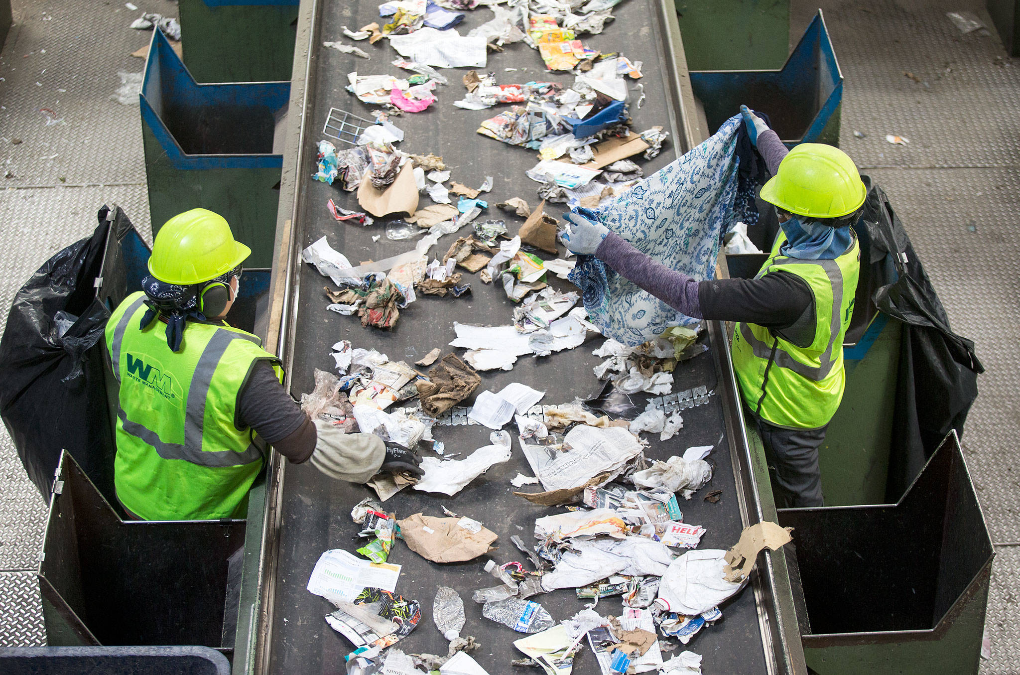 A worker pulls out a dress from recycled waste at Waste Management’s recycling center Tuesday in Woodinville. (Andy Bronson / The Herald)