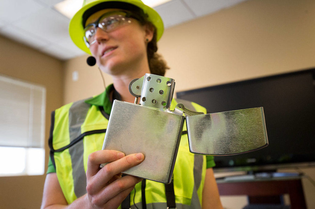 Hannah Scholes, education and outreach coordinator with Waste Management, holds up a lighter that was tossed into a recycle bin, full of lighter fluid, and ended up at Waste Management’s recycling center, Tuesday in Woodinville. (Andy Bronson / The Herald)
