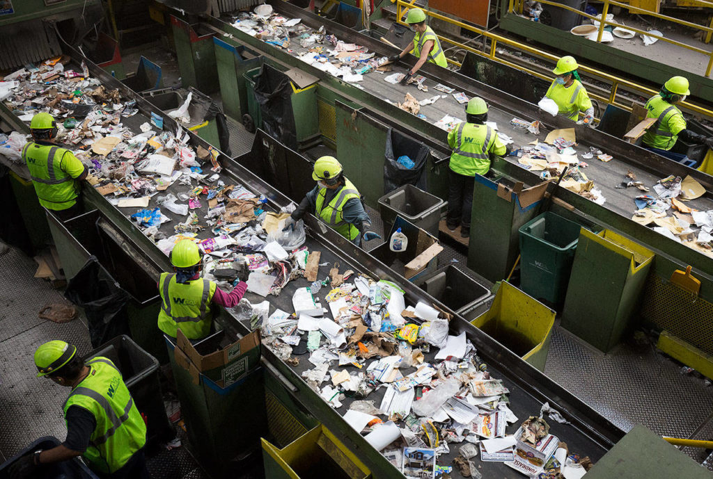 Workers remove items, such as plastic and clothes, from recycled waste at Waste Management’s recycling center Tuesday in Woodinville. Stricter standards for curbside recycling have been implemented since China is not accepting as much of our recycled waste anymore. (Andy Bronson / The Herald)
