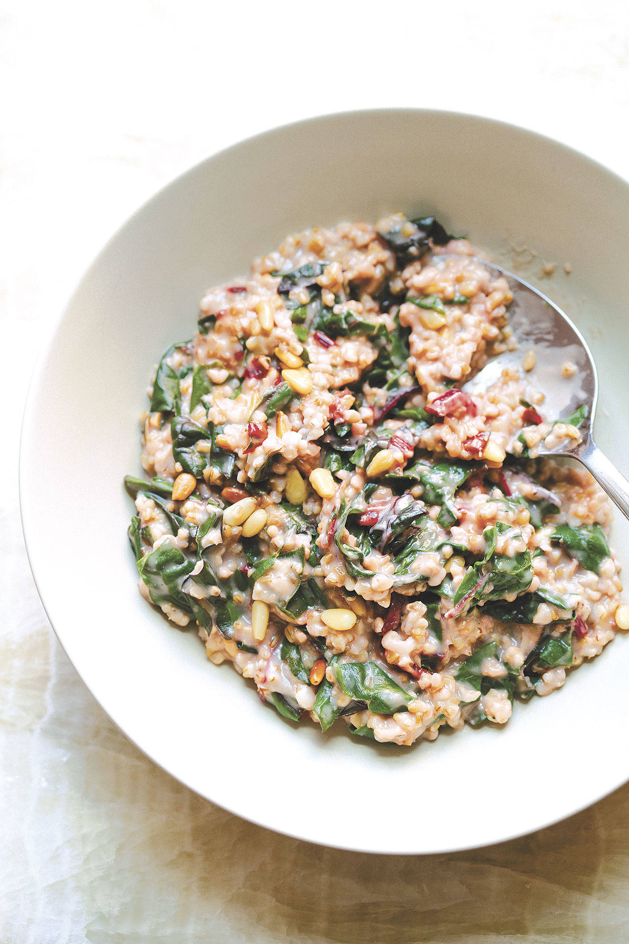 If you’re not vegetarian, creamy steel cut oats with rainbow chard and pine nuts can be topped with bacon crumbles and/or a fried or poached egg. (Masha Davydova)