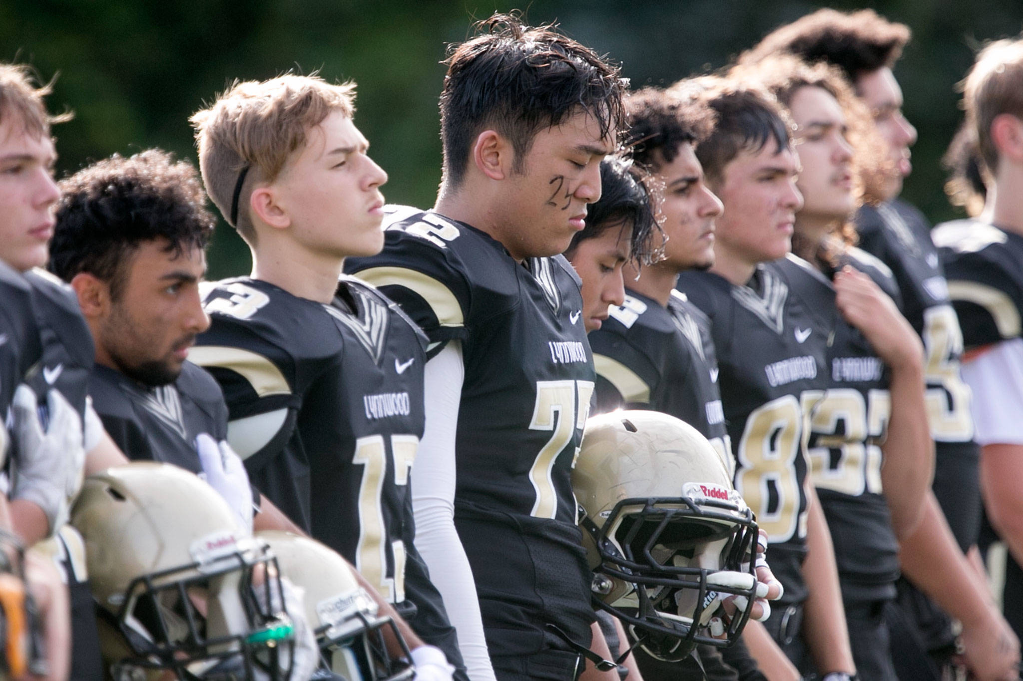 Lynnwood players stand for the national anthem with Lynnwood’s Matthew Pontoh (center) decorated with a deceased teammate’s number before a game against Nathan Hale Aug. 31, 2018, at Edmonds Stadium. (Kevin Clark / The Herald)