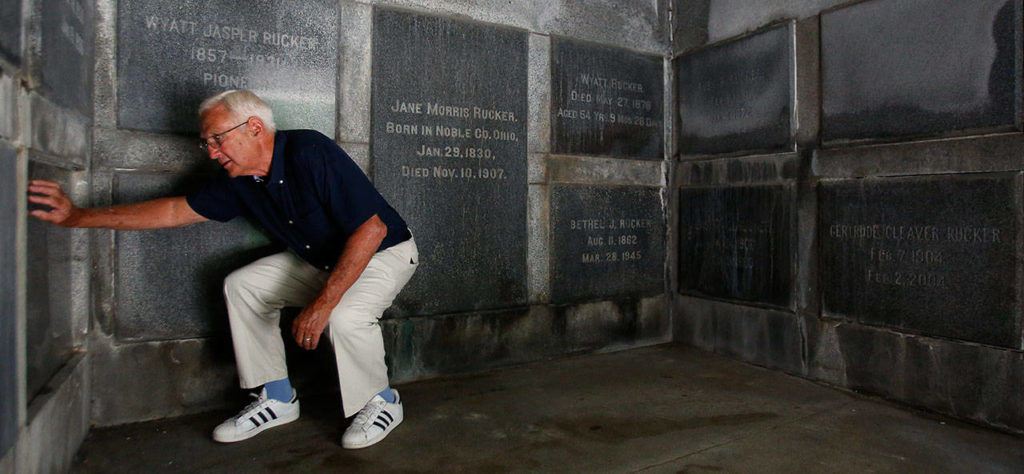 Bill Rucker bends down to view a cremation urn behind a glass panel in his family’s tomb. (Dan Bates / The Herald)
