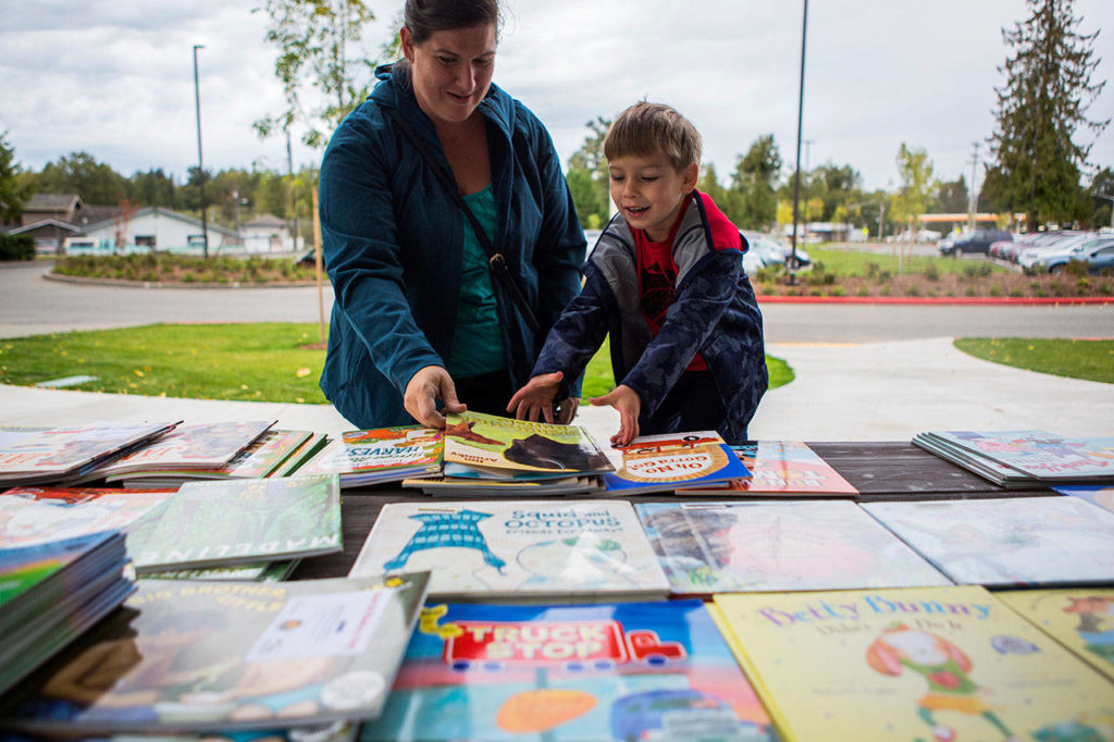 Samantha Grospe helps her son Everett Grospe, 4, pick a book during Lake Stevens Education Foundation Dolly Parton Imagination Library celebration on Sept. 21, 2018 in Lake Stevens, Wa. (Olivia Vanni / The Herald)
