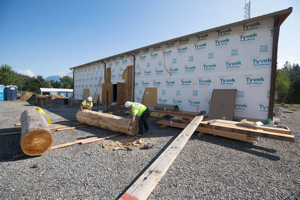 Workers move one of two cedar poles that will be part of the entrance to the Sauk-Suiattle Tribe’s new casino, Last Chance Bingo and Casino. (Andy Bronson / The Herald)
