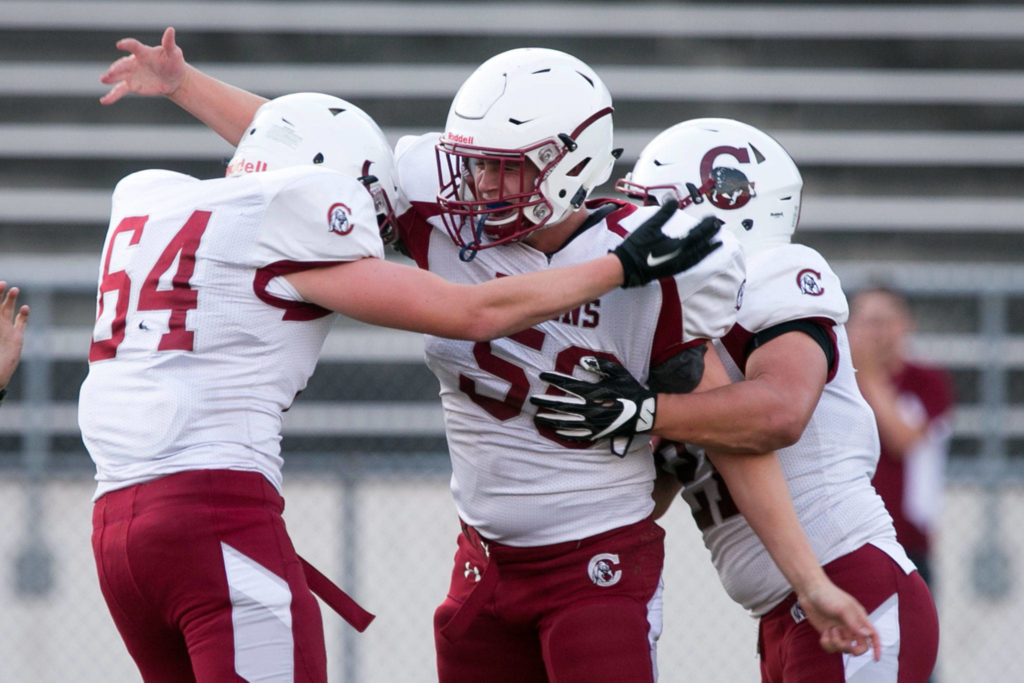 Cascade’s Jon Shaffer (center) celebrates a sack with teammates Cascade’s Billy Burgess (left) and Cascade’s Jacob Bauer (right) Friday night at Everett Memorial Stadium in Everett on August 31, 2018. Cascade won 32-22. (Kevin Clark / The Herald)
