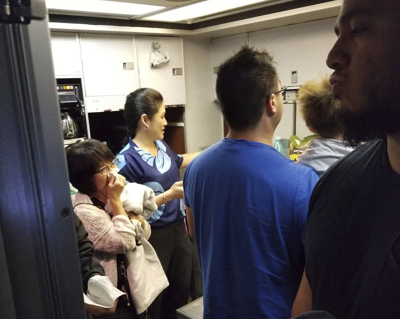 This Aug. 31 photo shows people gathered in a back galley on a Hawaiian Airlines flight from Oakland, California, to Kahului, Hawaii, after a can of pepper spray went off inside the plane. (Nicholas Andrade via AP)