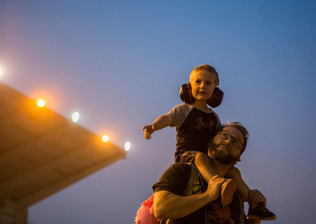 David Krenzer holds his son Logan Krenzer, 3, on his shoulders as they watch monster trucks at the Evergreen State Fair on Aug. 24, 2018 in Monroe, Wa. (Olivia Vanni / The Herald)
