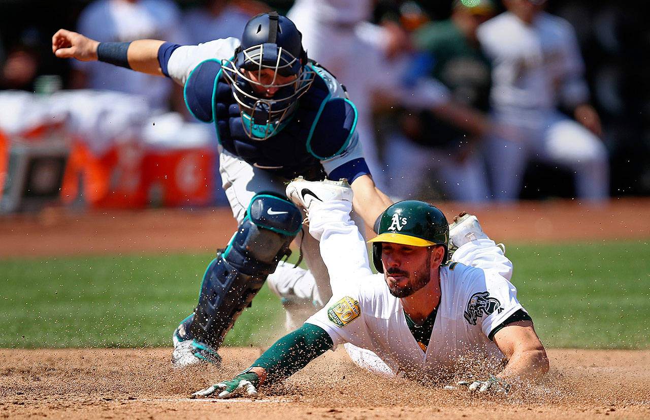 Oakland’s Matt Joyce slides underneath the tag of Seattle catcher Mike Zunino in the sixth inning of Sunday’s game in Oakland, California. Joyce scored on a single by Marcus Semien. (AP Photo/Ben Margot)