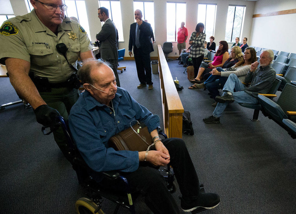 Passing the victims’ families, Clyde Reed, 83, is wheeled out of court in handcuffs after being sentenced, along with his wife, Faye Reed, 79, to 10 days in jail. Their son, John Reed, eventually was caught and convicted in the deaths of Monique Patenaude and Patrick Shunn. (Andy Bronson / The Herald)
