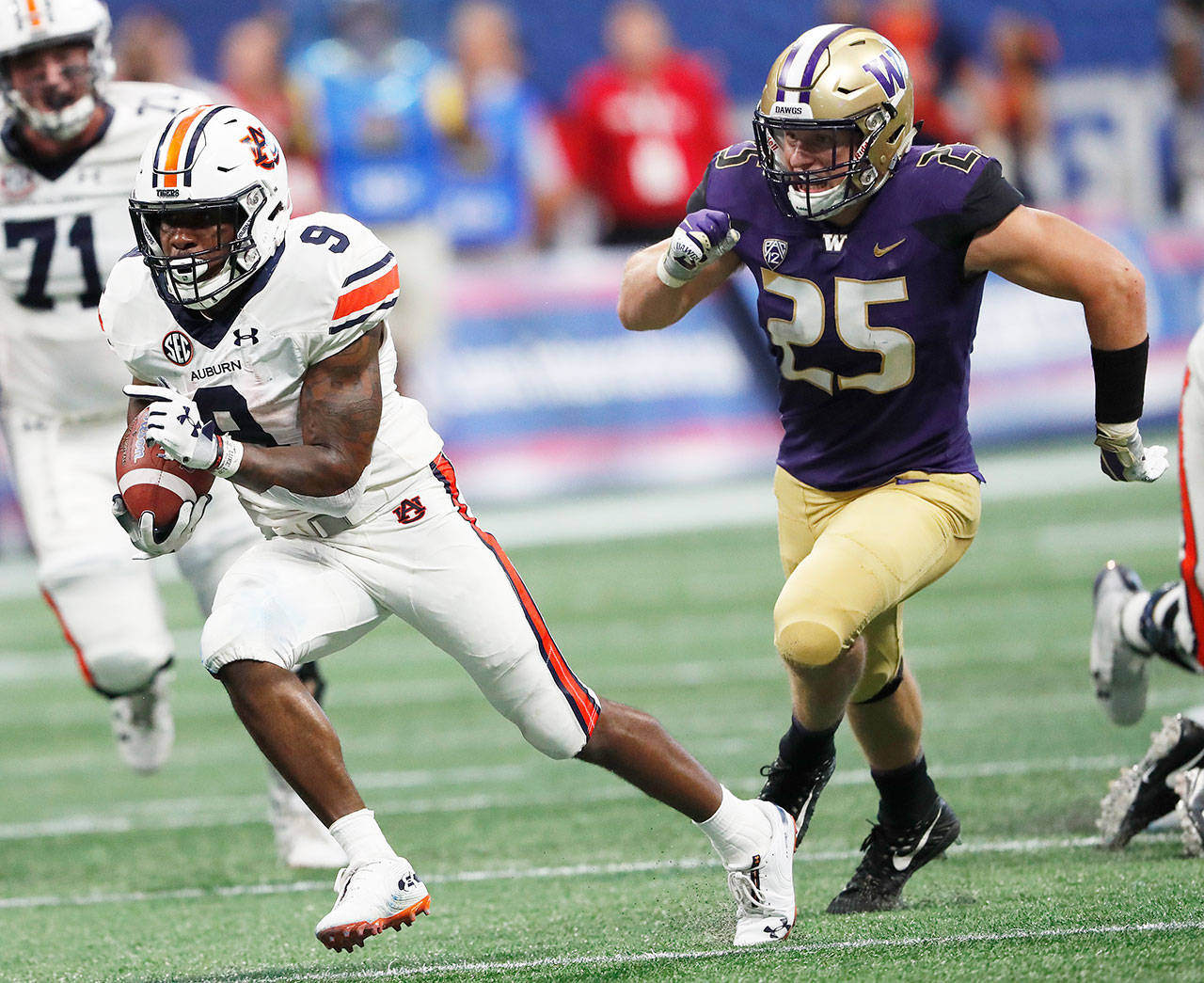 Auburn running back Kam Martin (9) runs as Washington linebacker Ben Burr-Kirven (25) gives chase during an NCAA football game Saturday in Atlanta. (John Bazemore / Associated Press)
