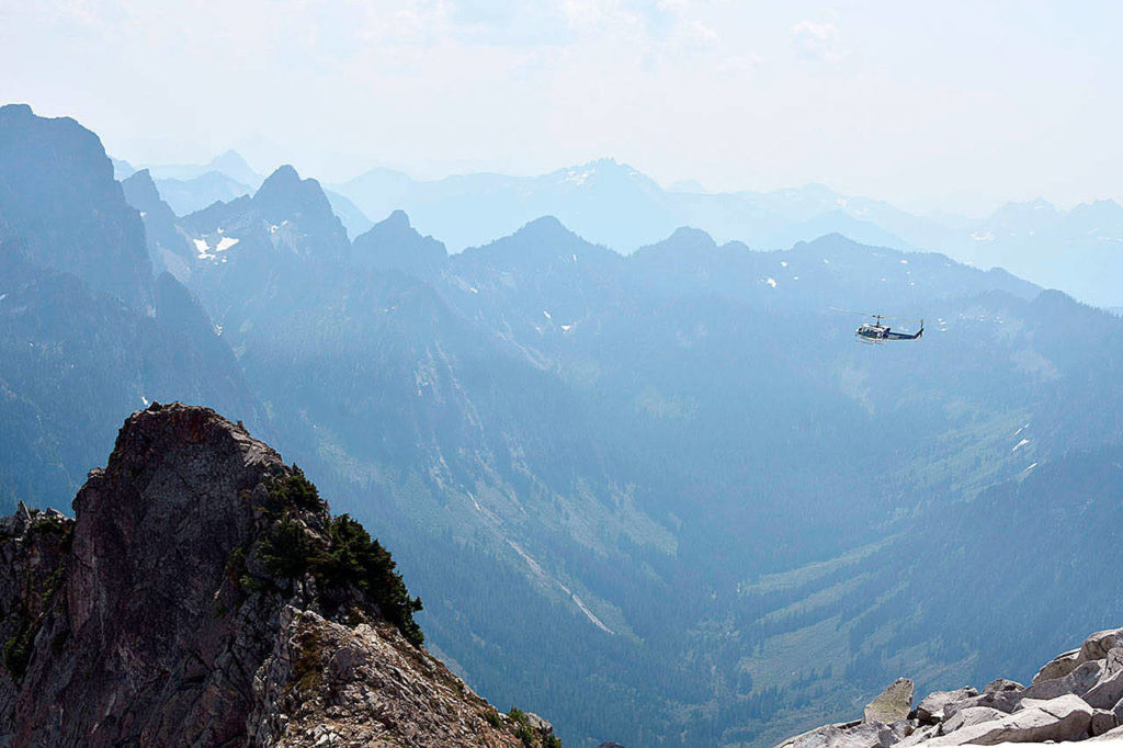 A helicopter soars southeast of Vesper Peak, searching for missing hiker Sam Sayers, 27, of Seattle. The background is a valley at the headwaters of the Sultan River. (Caleb Hutton / Herald file)

