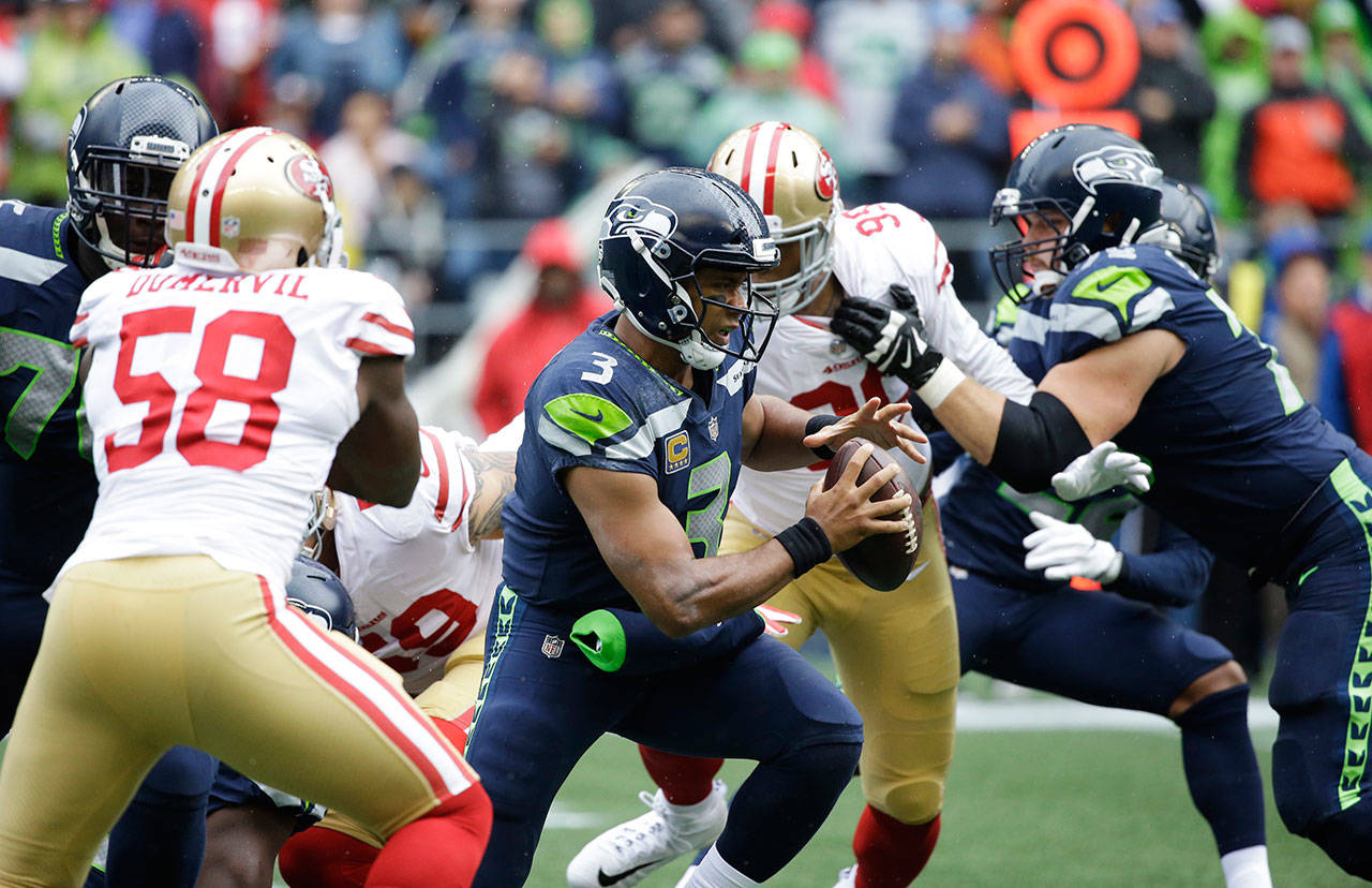 Seahawks quarterback Russell Wilson (center) scrambles during a game against the 49ers on Sept. 17, 2017, in Seattle. (AP Photo/Elaine Thompson)