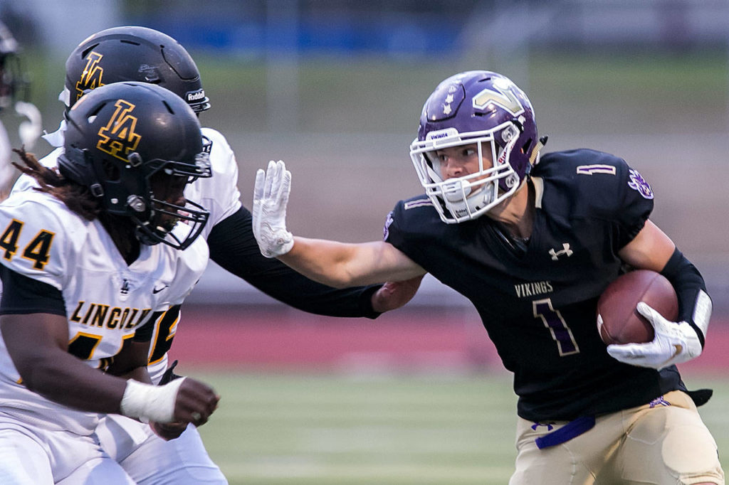 Lake Stevens’ Ian Hanson stiff-arms a pair of Lincoln defenders during a game on Sept. 7, 2018, at Lake Stevens High School. Lake Stevens won 38-21. (Kevin Clark / The Herald)
