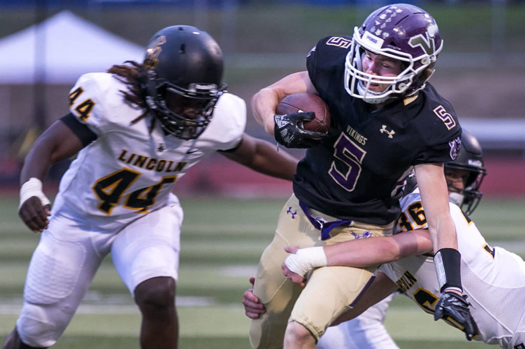 Lake Stevens’ Tom Lewis is tackled by Lincoln’s Troy Atkin with Lincoln’s Janoah Thomas (left) closing during a game on Sept. 7, 2018, at Lake Stevens High School. Lake Stevens won 38-21. (Kevin Clark / The Herald)
