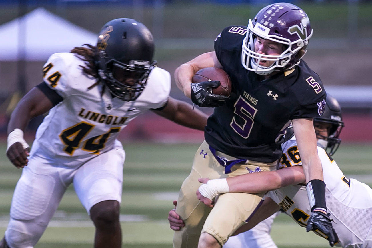 Lake Stevens’ Tom Lewis is tackled by Lincoln’s Troy Atkin with Lincoln’s Janoah Thomas (left) closing Friday at Lake Stevens High School. (Kevin Clark / The Herald)