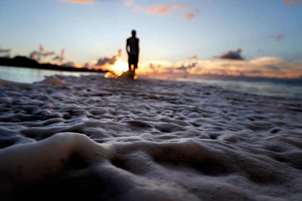 The surf washes up the shore at low tide as Andrew Lingle walks along the beach as Hurricane Florence approaches the east coast in Atlantic Beach, North Carolina, on Wednesday, Sept. 12. (AP Photo/David Goldman)
