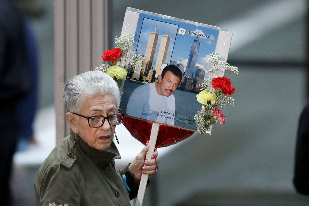 A woman arrives on Tuesday in New York, at the 17th anniversary of the terrorist attacks on the United States, with a sign bearing photo memories for Wilder Gomez. Gomez, from Colombia, was a bartender at Windows on the World on the 103rd floor of the World Trade Center when it was attacked. (AP Photo/Mark Lennihan) 

