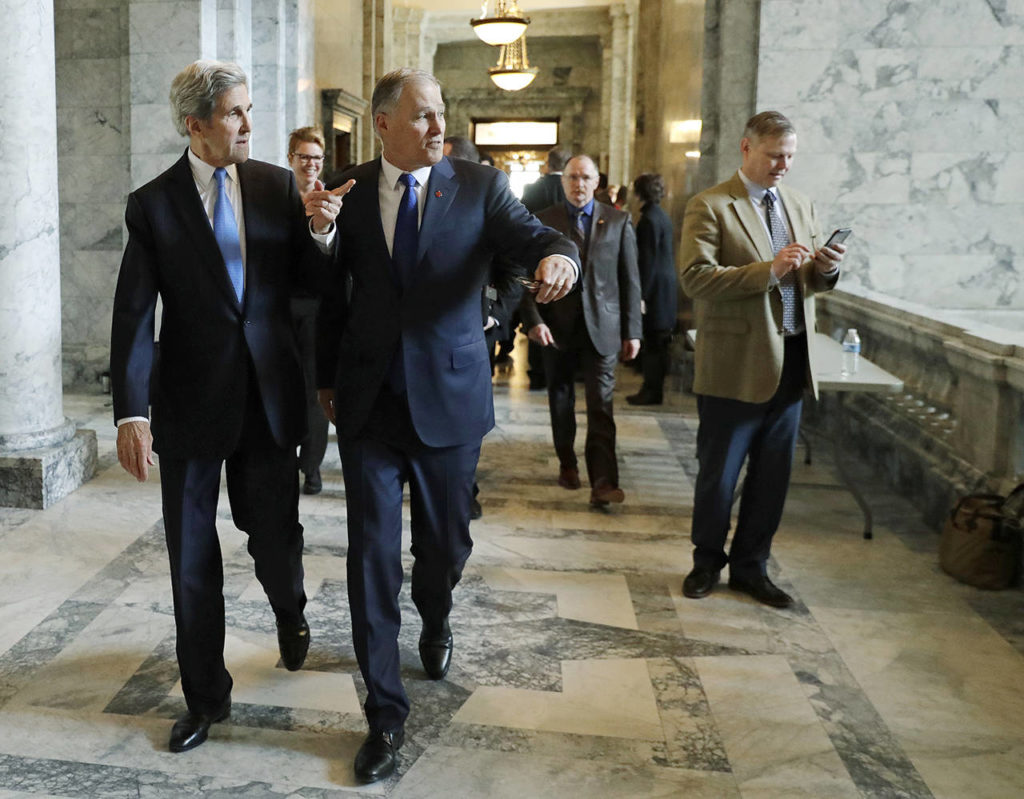 Former U.S. Secretary of State John Kerry (left) walks with Gov. Jay Inslee (center) on Feb. 13, 2018, during a visit hosted by Inslee to participate in meetings discussing the governor’s proposed tax on fossil fuel emissions. (AP Photo/Ted S. Warren, file)
