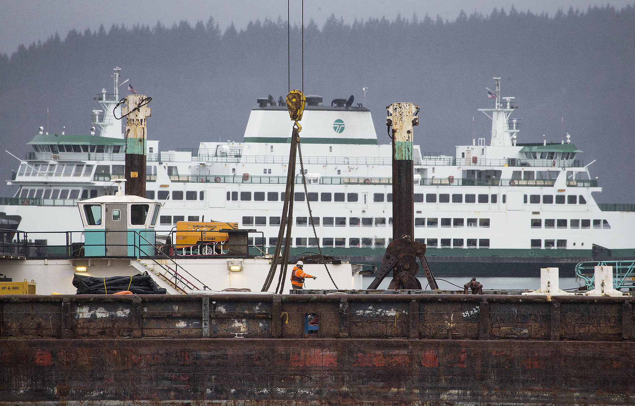A worker directs others on a barge as construction continues earlier this year at the new Mukilteo ferry dock. Ferries project employees recently met with Mukilteo City Council members in a work session for an update about the $167 million project. (Andy Bronson / Herald file)