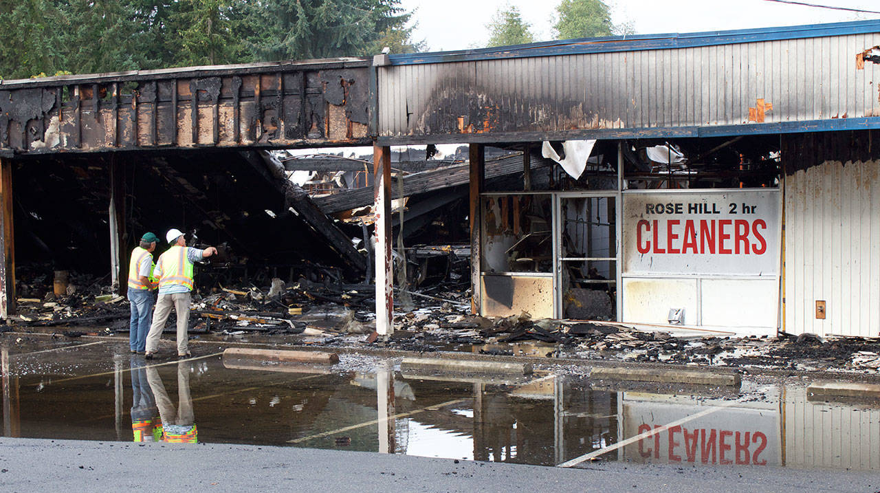 Kirkland firefighters and Puget Sound Energy staff examine the aftermath of a four-hour fire that destroyed the Rose Hill Village. (Kailan Manandic / Kirkland Reporter)