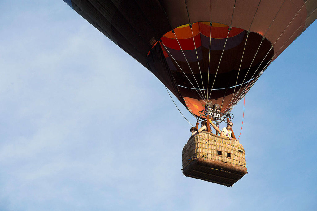 Jill Van Rawley peers out from the basket as Woodward takes riders over Snohomish Valley. The hot air balloon ride was a first for Van Rawley, of Philadelphia. (Andy Bronson / The Herald)
