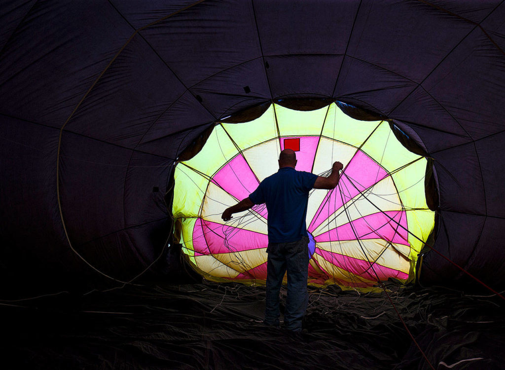 As the balloon fills, pilot Jay Woodward, owner of Balloon Depot, straightens lines inside his hot air balloon. Licensed by the Federal Aviation Administration, Woodward has been piloting hot air balloons for 20 years. (Andy Bronson / The Herald)
