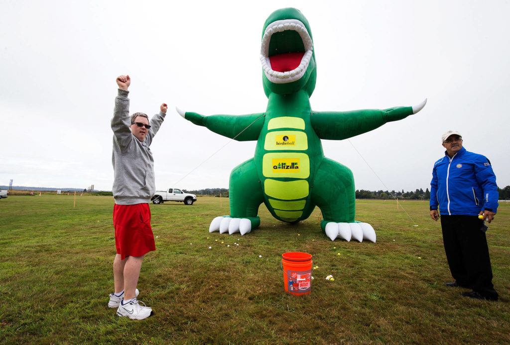 Brian Gouge, of Edmonds, raises his arms in joy after throwing a golfball into the mouth of Golfzilla at the annual Friendship Festival at Harvey Field on Saturday, Sept. 15, 2018 in Snohomish, Wa. The event was put on by the Down Syndrome Association of Snohomish County.(Andy Bronson / The Herald)
