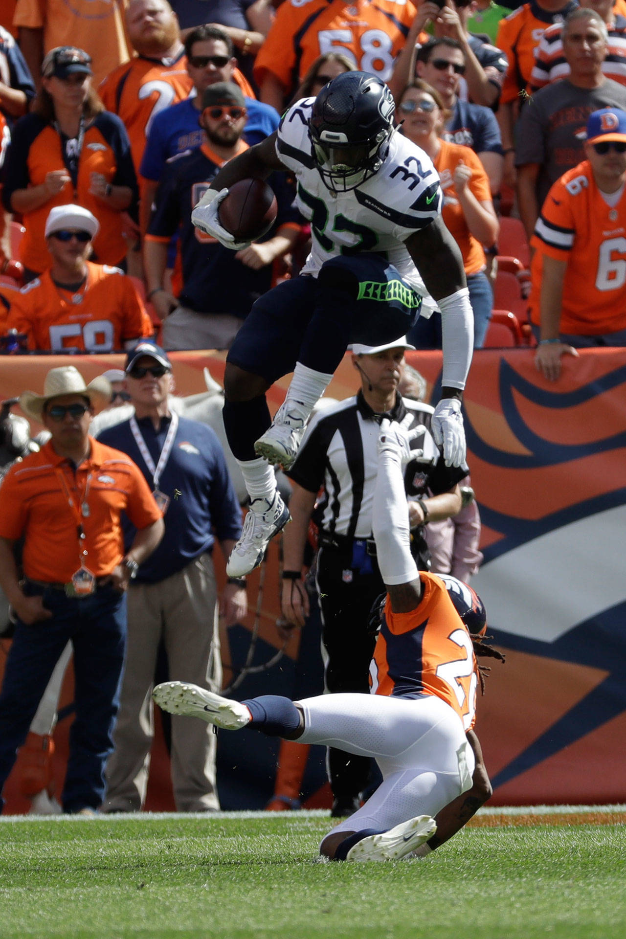 Seattle’s Chris Carson leaps over Denver’s Bradley Roby during the first half of a Sept. 9 game in Denver. (Jack Dempsey / Associated Press)