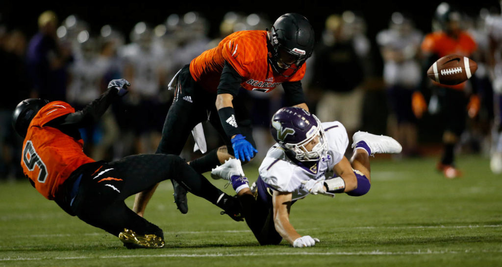 Two Monroe players break up a pass intended for Lake Stevens’ Ian Hanson during Friday night’s game in Monroe. (Andy Bronson / The Herald)

