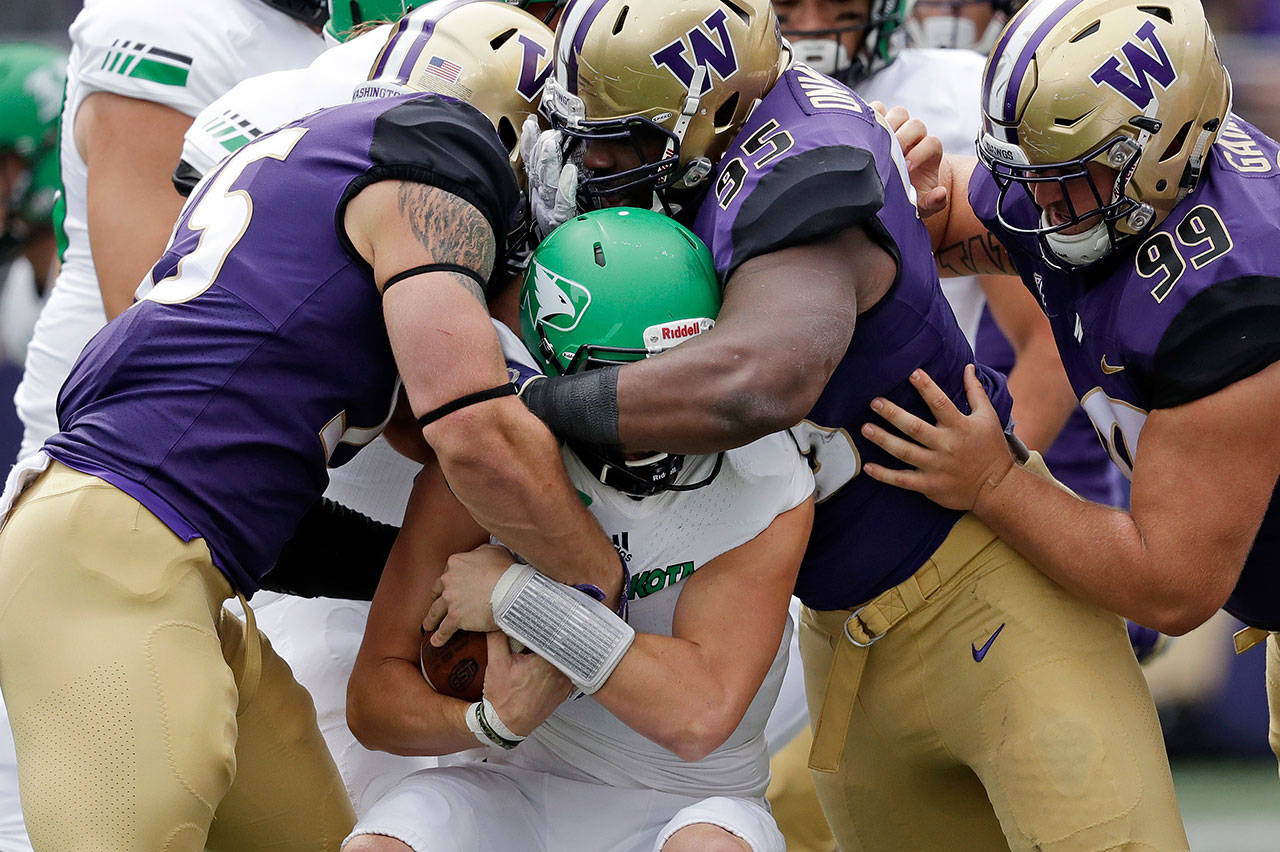 Washington’s Ryan Bowman (left) Levi Onwuzurike (95) and Greg Gaines (99) wrap up North Dakota quarterback Nate Ketteringham in the first half of a game on Sept. 8, 2018, in Seattle. (AP Photo/Elaine Thompson)