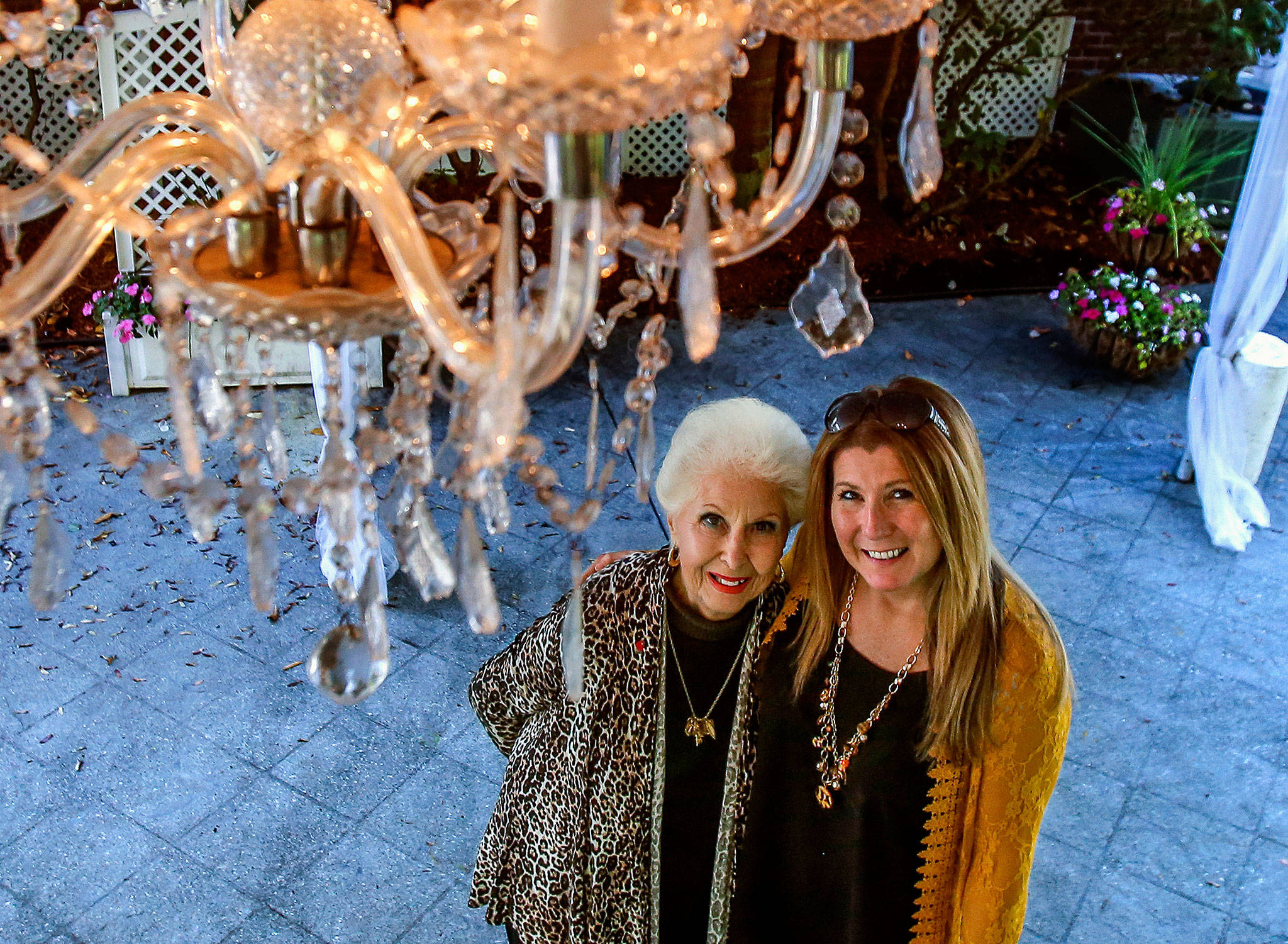 Donna Leifer, 88, (left) and her daughter Melody-Leifer Fitzmaurice, 50, glance up past one of the three chandeliers hanging beneath white fabric canopies that have covered countless weddings over the last 27 years at Marysville’s Leifer Manor. (Dan Bates / The Herald)