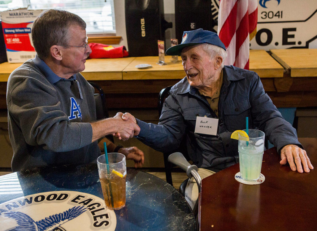 World War II veteran Buck Weaver, 100 (right), shakes Charlie Sylling’s hand at the Stanwood Fraternal Order of Eagles post Thursday. (Olivia Vanni / The Herald)
