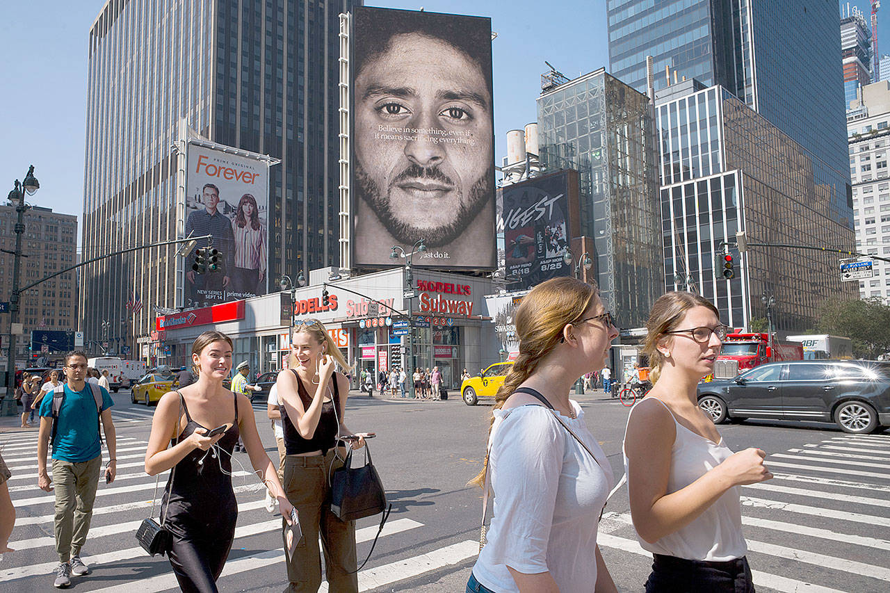 People in New York walk past a Nike advertisement featuring former San Francisco 49ers quarterback Colin Kaepernick, known for kneeling during the national anthem to protest police brutality and racial inequality. (Associated Press file)