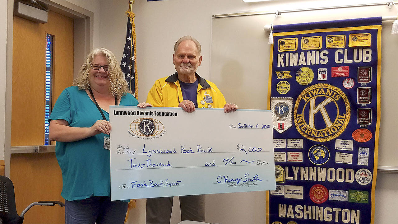 Lynnwood Food Bank Director Alissa Jones receives $2,000 from Lynnwood Kiwanis President Harvey Smith. (Contributed photo)