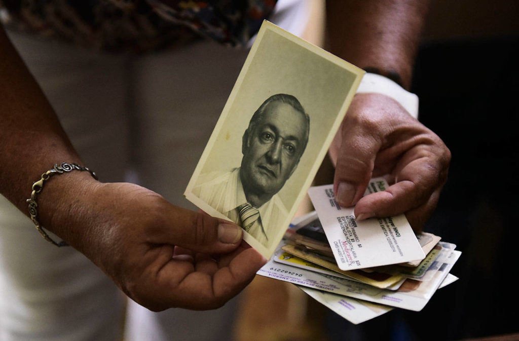 Nerybelle Perez holds a picture, in June 2017, of her father, World War II veteran Efrain Perez, who died inside an ambulance after being turned away from the largest public hospital when it had no electricity or water, days after Hurricane Maria hit Guaynabo, Puerto Rico. Researchers from George Washington University hired by Puerto Rico’s government estimated in Aug. 2018 that 2,975 people had died because of Maria in the six months after landfall, a number Puerto Rico accepted as official. (Carlos Giusti / Associated Press file photo)
