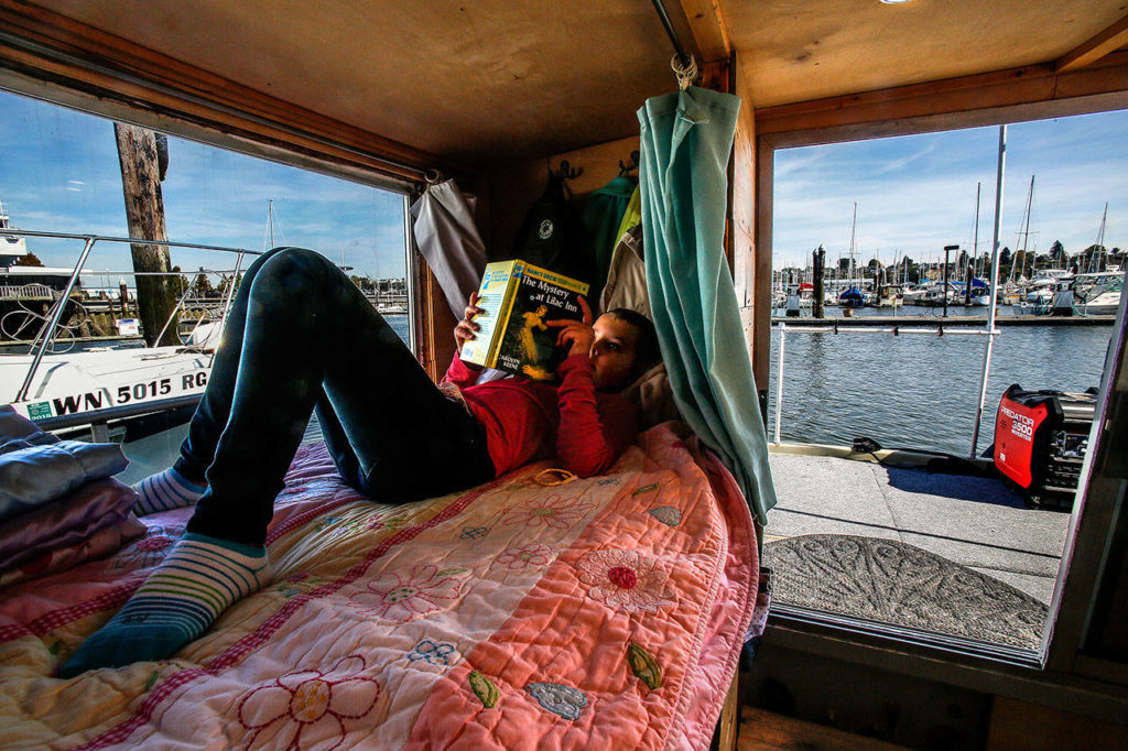 On her cozy bed overlooking the Everett Marina, the Everett Yacht Club and boats of all kinds, Arianna reads a Nancy Drew book, The Mystery at Lilac Inn. (Dan Bates / The Herald)
