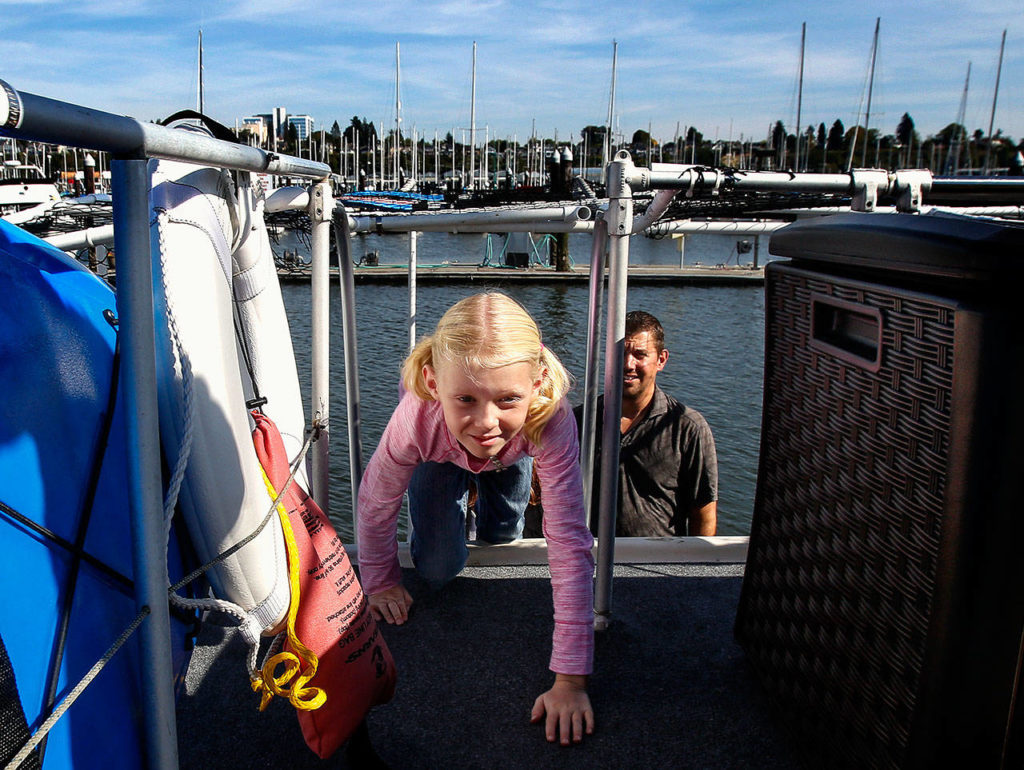 At the back of the Taiseys’ houseboat, Felicity, 7, climbs carefully up the ladder and onto the upper deck of the boat where there is enough floor space for the family to spread out and play a game. (Dan Bates / The Herald)
